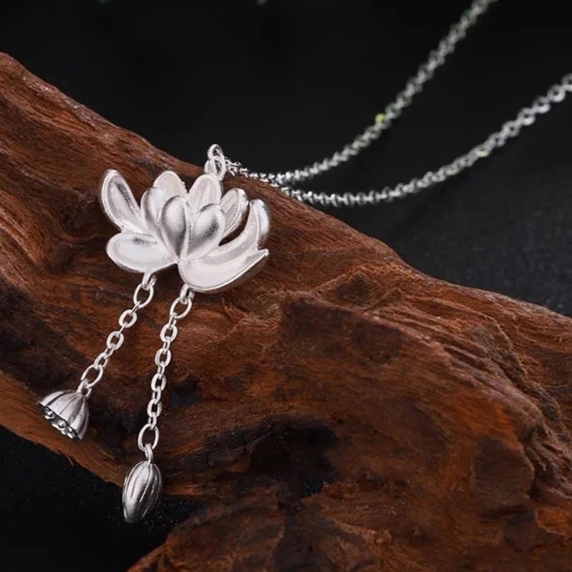 Silver lotus flower necklace with chain on a wooden surface
