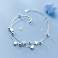 Silver bracelet with star and moon charms on a light blue background